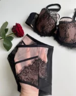 hand-is-holding-black-and-beige-panties-from-the-inside-with-a-lace-bra-and-rose-nearby