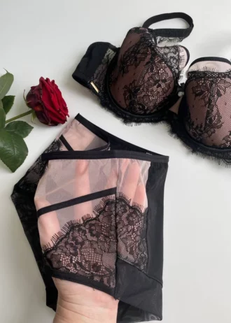 hand-is-holding-black-and-beige-panties-from-the-inside-with-a-lace-bra-and-rose-nearby