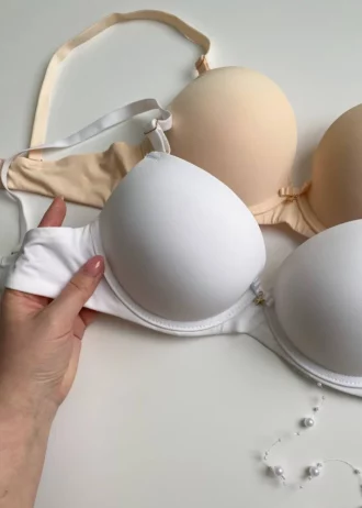 hand-is-holding-smooth-classic-white-and-beige-bras-with-push-up-and-bows-C-cup