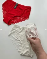 hand-is-holding-white-and-red-cotton-high-waisted-slips-with-pieces-of-lace